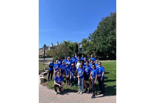A group of people in blue shirts are posing for a photo in a park.